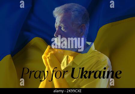 Doppelte Exposition von betenden reifen Mann und ukrainische Flagge. Betet für die Ukraine Stockfoto