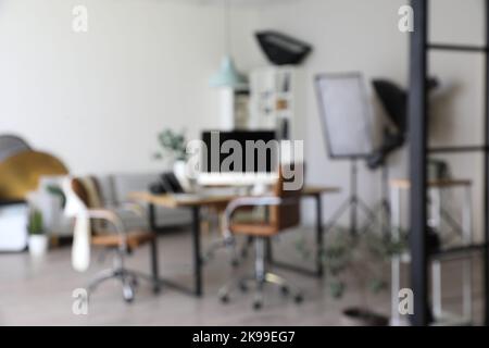 Verschwommenes Interieur eines modernen Studios mit dem Arbeitsplatz des Fotografen und professioneller Ausrüstung Stockfoto