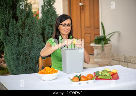 Kaukasische Hausfrau Frau Scheiben Karotten Salat Zutaten für Abendessen im Freien vorzubereiten. Stockfoto