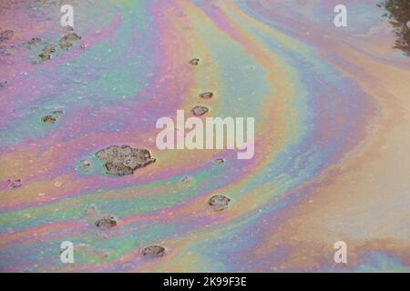 Benzin verschüttete sich auf der Straße in einer Pfütze aus buntem Wasser Stockfoto