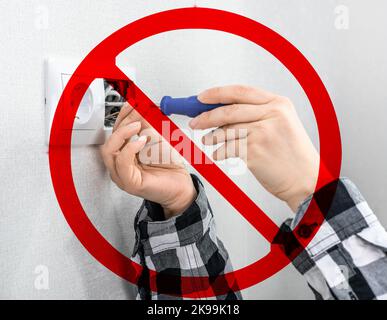 Gefahr eines elektrischen Schlags, wenn der Schraubendreher nicht richtig gehalten wird. Gefährliche Arbeiten mit Hochspannungsnetzwerken. Hand mit Schraubendreher für die Reparatur Stockfoto