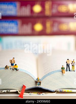 Nahaufnahme von Miniaturfiguren einer Gruppe von Menschen, die Buch und Zeitung lesen. Stockfoto