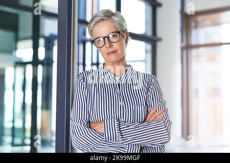 Erfolg wird verdient, nicht überliefert. Porträt einer attraktiven reifen Geschäftsfrau, die mit gefalteten Armen in ihrem Büro posiert. Stockfoto