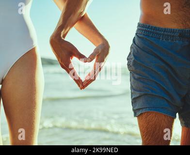 Ich habe dich mir sehr am Herzen gelegen. Nahaufnahme eines Paares, das mit den Händen am Strand eine Herzform formt. Stockfoto