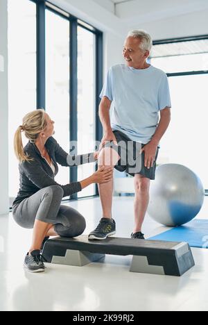 Ich fühle mich bereits stärker. Ganzkörperaufnahme einer freundlichen Physiotherapeutin, die mit einer älteren Patientin zusammenarbeitet. Stockfoto