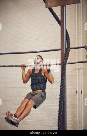 Machen Sie Ihre Ziele fest im Griff. In voller Länge ein hübscher junger Mann, der beim Training im Fitnessstudio zieht. Stockfoto