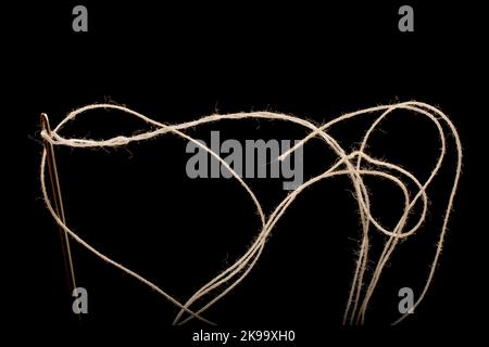 Nadel und weiße Baumwolle, gezwirntes Garn auf Rolle zum Nähen. In der Textil- und Textilindustrie verwendetes Gewinde. Schwarzer Hintergrund Stockfoto