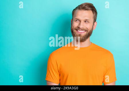 Foto-Porträt von attraktiven jungen Mann toothy lächelnd aussehen tricky leeren Raum tragen trendy orange Kleidungsstück isoliert auf cyanfarbenem Hintergrund Stockfoto