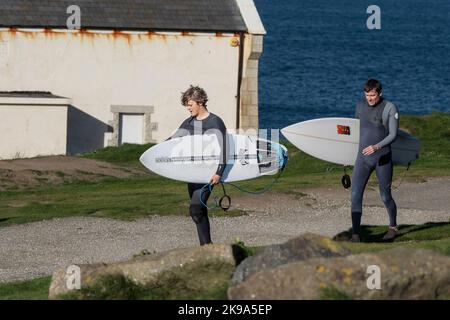 Zwei Surfer, die ihre Surfboards tragen und den Küstenpfad bei Newequay in Cornwall in England in Großbritannien entlang wandern. Stockfoto