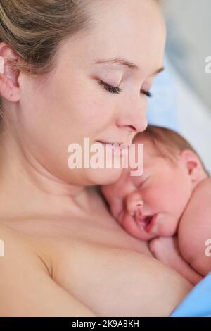 Eine schöne junge Mutter und ihr neugeborenes Mädchen schliefen zusammen in einem Krankenhausbett. Stockfoto