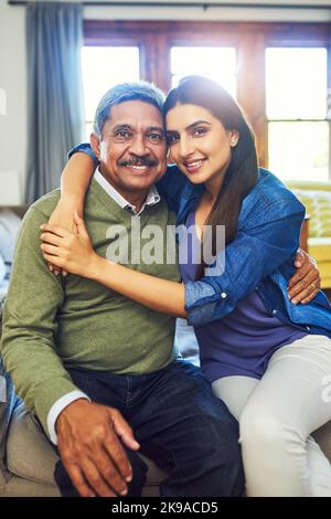 Sie macht mich zu einem so stolzen Vater. Porträt eines fröhlichen älteren Mannes, der mit seiner Tochter posiert, während er sich zu Hause auf der Couch entspannt. Stockfoto