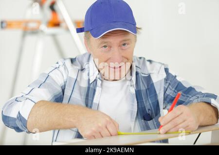 Leitender Zimmermann mit Maßband Stockfoto