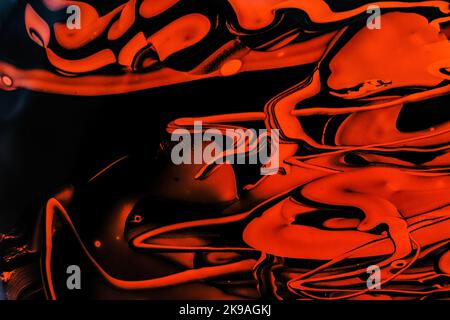 Foto von oranger und schwarzer flüssiger Farbe mit Reflexionen. Abstrakter Hintergrund mit wirbelnder Farbwirkung. Flüssige Acryl-Grafik mit bunt gemischt Stockfoto