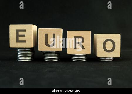 Abschwächung der Euro-Währung, Wertabwertung und Abwertungskonzept. Abnehmender Münzstapel auf dunkelschwarzem Hintergrund. Stockfoto