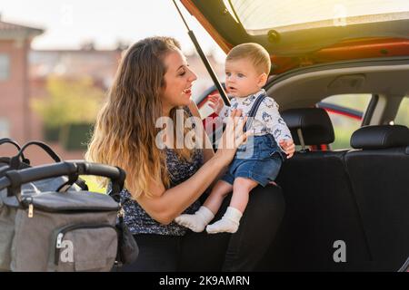 Mutter mit ihrem Sohn hinter dem Wagen, der die Reise vorbereitete Stockfoto