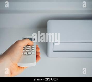 Hand, die Fernbedienung auf die Klimaanlage. Stockfoto