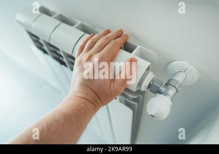 Mannes hand Überprüfung Temperatur der Heizung Heizkörper. Stockfoto