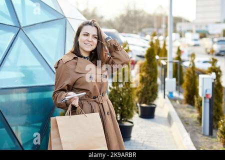 Schöne glückliche junge Mädchen zu Fuß mit Einkaufstasche auf den Straßen der Stadt, während Sie einkaufen. Stockfoto