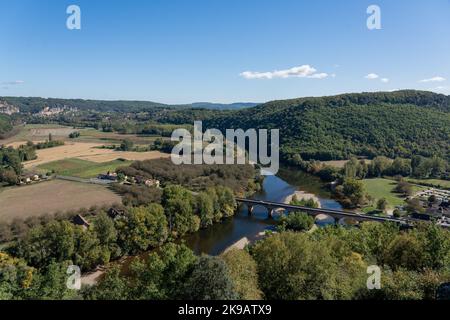 Blick auf den Fluss Dordogne, die Brücke mit mehreren Bögen und die malerische Landschaft von oben im Schloss Castelnaud-la-Chapelle, blauer Himmel Stockfoto