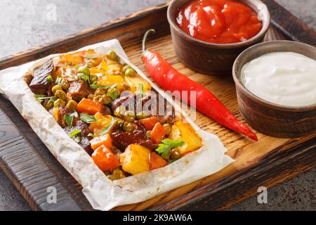 Türkischer Kebab in Papier Kagit Kebabi Nahaufnahme auf einem Holztablett auf dem Tisch. Horizontal Stockfoto