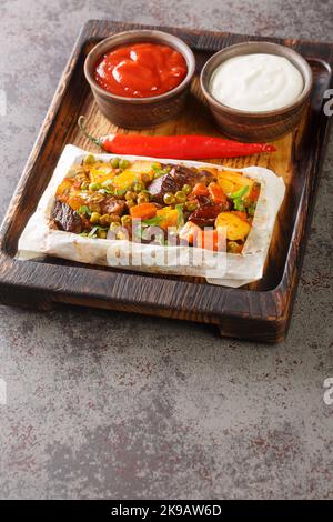 Sebzeli kagit kebami traditionelle türkische Lebensmittel Fleisch mit Gemüse in fettfestem Papier eingewickelt, Kebab Nahaufnahme auf einem Teller auf dem Tisch. Vertikal Stockfoto