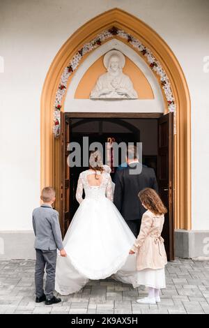 Braut und Bräutigam warten vor der Kirche auf die Hochzeitszeremonie. Stockfoto