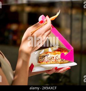 Traditionelle französische Torte. Quiche Loraine mit Pilzen, Brokkoli, Tomaten und Käse. In rosa Take-away-Box in weiblichen Händen Stockfoto