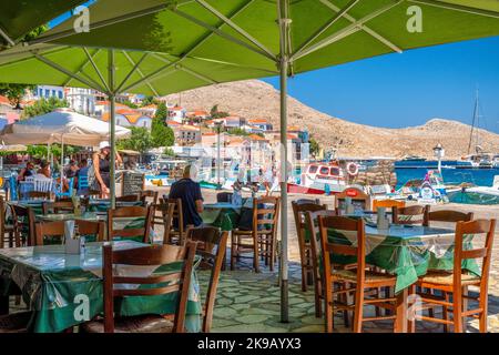 Halki, Griechenland - 6. Juli 2022: Griechische Taverne mit Blick auf das Meer auf der kleinen malerischen Insel Halki (Chalki) in Griechenland Stockfoto