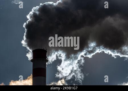 Dunkler Rauch und Dampf aus dem Kamin in der Fabrik gegen den Himmel Stockfoto