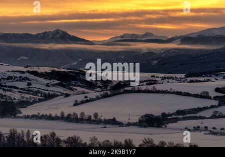 Verschneite Winterberglandschaft und farbenprächtiger Himmel bei Sonnenaufgang über den Hügeln Sina, Dumbier und Chopok in der Niederen Tatra in der Slowakei. Stockfoto
