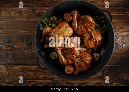 Gebratenes Hähnchen mit Backäpfeln und Knoblauch in einer gusseisernen Pfanne Stockfoto