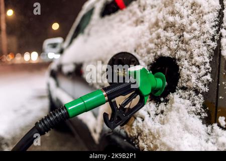 Verschneite Autobefüllung an der Tankstelle in der Nacht Stockfoto