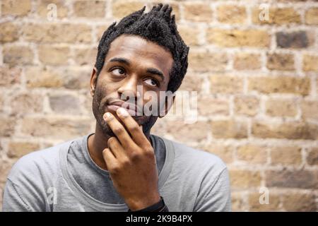 Emotionen und Ausdrücke: Nachdenklich. Ein Blick der Kontemplation auf das Gesicht eines jungen Mannes. Aus einer Reihe verwandter Bilder. Stockfoto