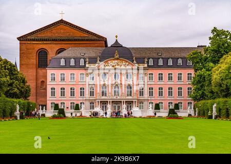 Berühmte Ansicht des Kurfürstlichen Palastes in Trier, Deutschland mit der Basilika dahinter. Der Rasen und die Blumenbeete vor dem Haupteingang nach Süden... Stockfoto