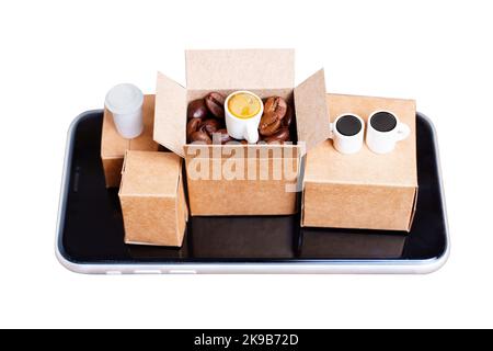Kleine Versandkartons mit gerösteten Kaffeebohnen und Kaffeetassen auf einem Smartphone auf weißem Hintergrund isoliert platziert. Kreativer E-Commerce und Kaffee-support Stockfoto
