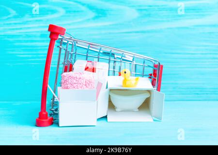 Babywanne und Accessoires Online-Shopping: Mini-Push-Trolley mit kleinen Lieferboxen mit winziger Badewanne, gelber Ente und rosa Handtuch isoliert Stockfoto