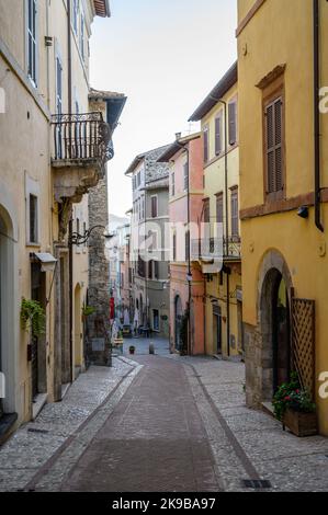 Eine typische Straßenszene in der Altstadt von Spoleto mit traditionellen Steinhäusern und engen Gassen, die am frühen Morgen fotografiert wurden. Umbrien, Italien. Stockfoto