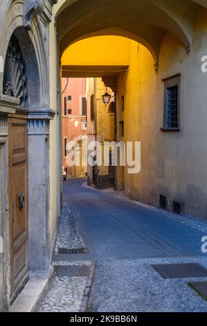 Rustikaler Charme: Eine typische Straßenszene in der Altstadt von Spoleto mit traditionellen Steinhäusern und einer engen Gasse, die am frühen Morgen fotografiert wurde. Umbrien, Italien. Stockfoto