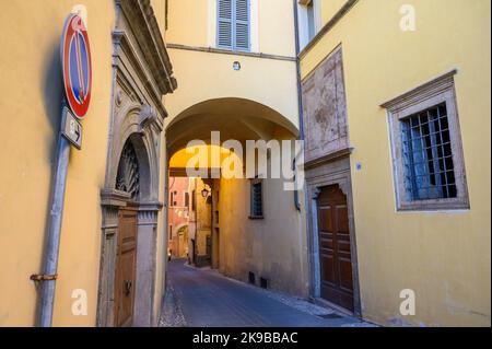 Rustikaler Charme: Eine typische Straßenszene in der Altstadt von Spoleto mit traditionellen Steinhäusern und einer engen Gasse, die am frühen Morgen fotografiert wurde. Umbrien, Italien. Stockfoto