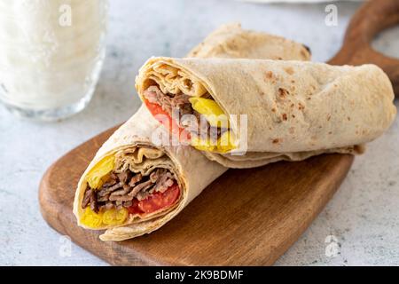 Türkische Fleisch-Döner-Verpackung auf grauem Hintergrund. Traditionelle Aromen. Döner Kebab aus Rind und Lamm. Nahaufnahme Stockfoto