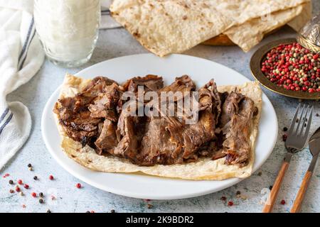 Türkischer Fleischspender auf grauem Hintergrund. Traditionelle Aromen. Döner Kebab aus Rind und Lamm. Nahaufnahme Stockfoto