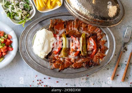 Türkischer iskender Kebab auf grauem Hintergrund. Traditionelle Aromen. Döner Kebab aus Rind und Lamm. Nahaufnahme Stockfoto