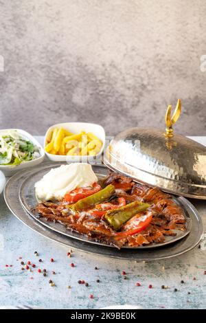 Türkischer iskender Kebab auf grauem Hintergrund. Traditionelle Aromen. Döner Kebab aus Rind und Lamm. Nahaufnahme Stockfoto