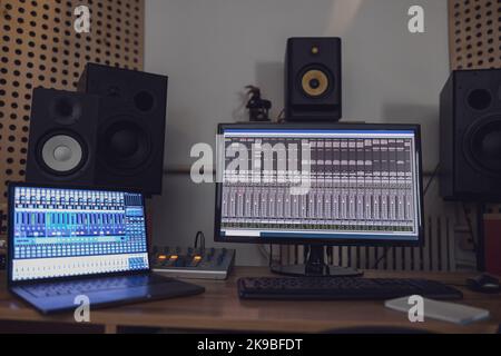 Overhead-Ansicht von eingeschaltetem Laptop und Monitor-Bildschirm auf dem Tisch in einem Rundfunk- und Aufnahmestudio Stockfoto