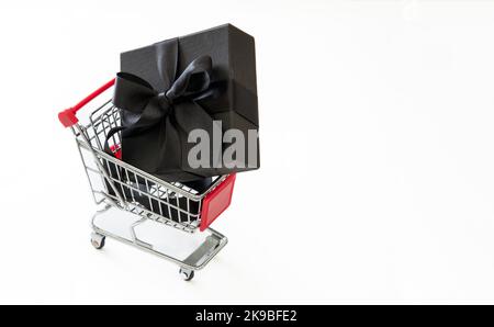 Black Friday Sale, Weihnachtsgeschenke. Geschenkbox in einem Einkaufswagen isoliert auf weißem, kopiertem Platz. Stockfoto