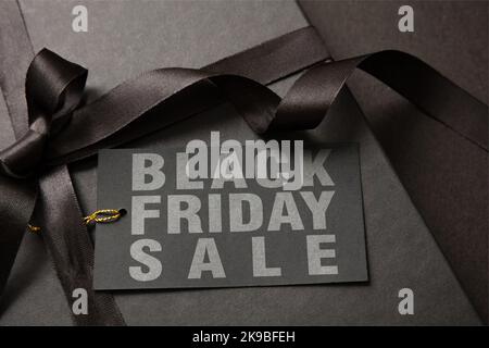 Schwarzer Freitag Sale-Text auf einem Geschenkanhänger. Einkaufsbox mit Etikett und Band, Nahaufnahme. Packen von Weihnachtsgeschenken Stockfoto