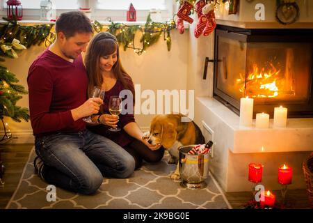 Junges Paar in der Nähe des Kamins zu Hause Winter umarmt Nahaufnahme Stockfoto