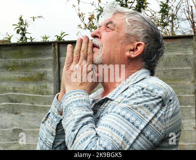 Mann, der zu Gott betet. Die Hände schrammten zusammen und schauten in den Himmel. Er braucht Hilfe, da er ernsthafte Probleme hat und auf eine Intervention von Devine hofft. Stockfoto