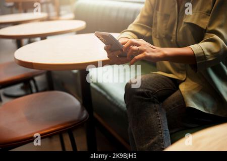 Nahaufnahme der Hand einer Frau mit einem Smartphone während der Kaffeepause. Stockfoto