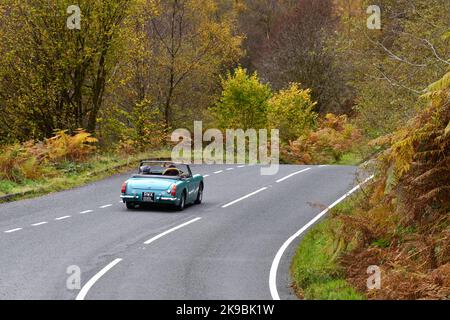 Ein MG Midget (1973) Sportwagen, der im Herbst auf einer Landstraße in Schottland, Großbritannien, von oben nach unten gefahren wird Stockfoto